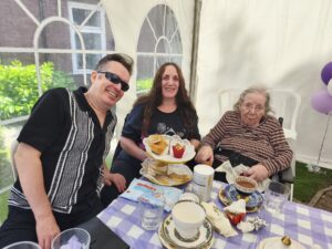 Three guests gathered beside a tiered cake stand in The Grove’s marquee.