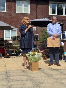 Guests speaking beside a microphone and flowers on The Grove’s terrace.